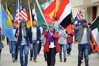 Students, faculty and staff participating in the march of flags during the annual homecoming parade.